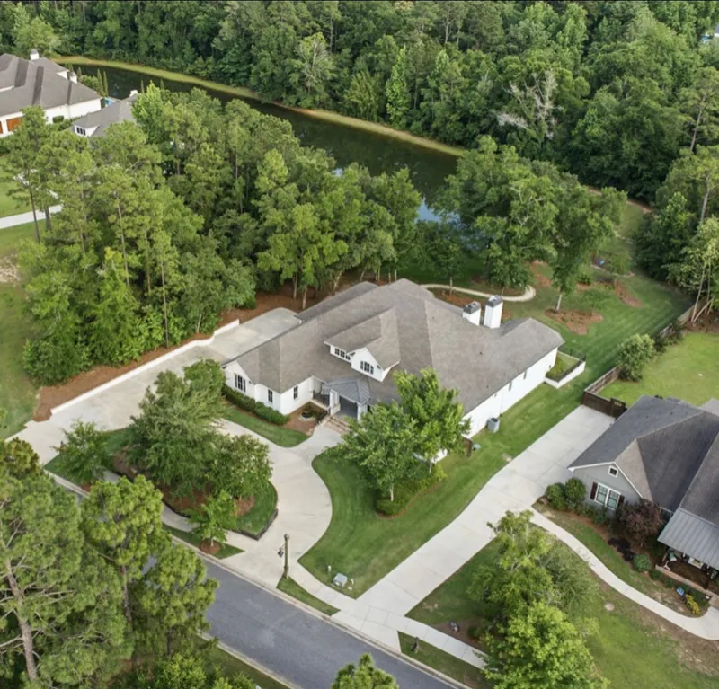 Aerial view of a home and landscaped lawn surrounded by trees
