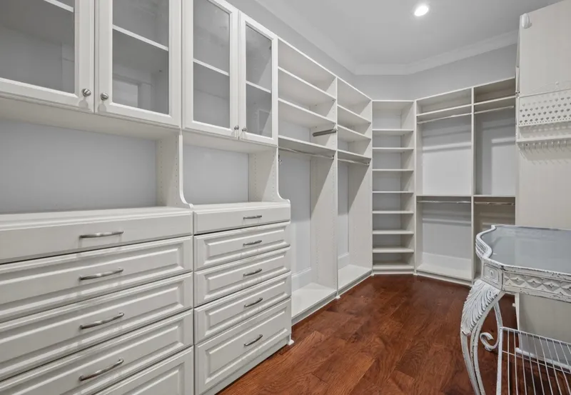 Walk-in closet with white drawers, glass-front cabinets and open shelving