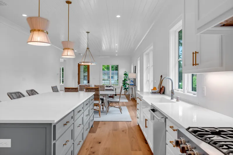 View along a white kitchen island toward the dining and living areas