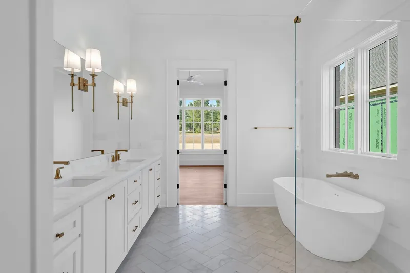 Bathroom with a long white vanity and a freestanding tub beneath a window