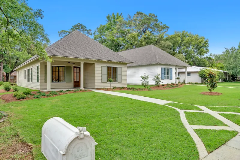 Cottage with a covered front porch and a green lawn
