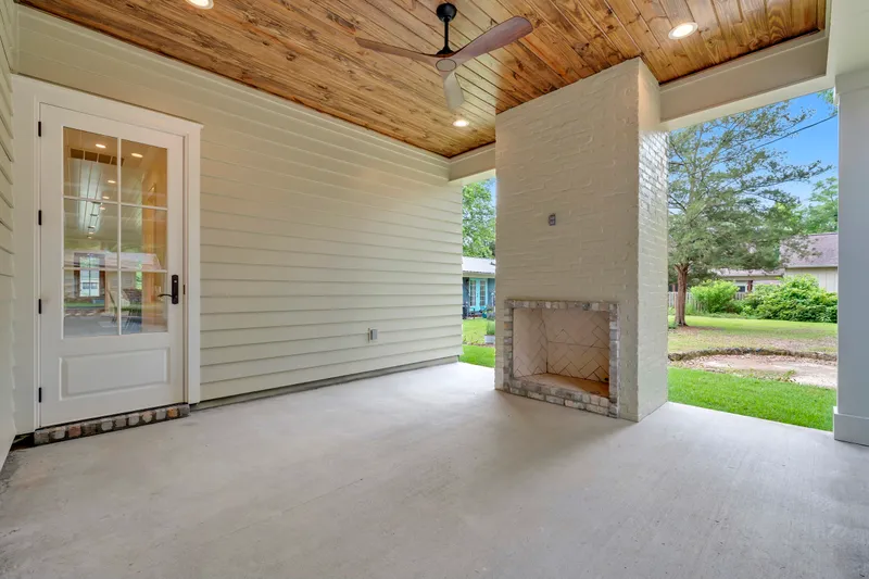 Covered porch with a wood ceiling, ceiling fan and outdoor fireplace