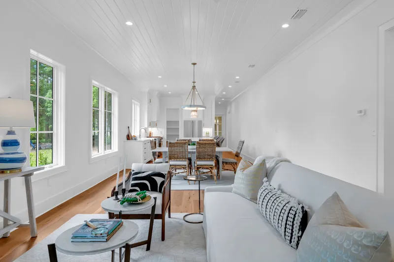 Living and dining area with tall windows, a sofa and wood floors