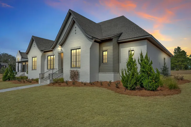 Angled view of a white gabled home and landscaped lawn at sunset