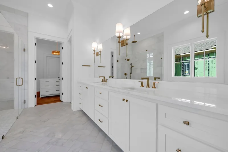Long white bathroom vanity with twin mirrors and brass-colored wall lights