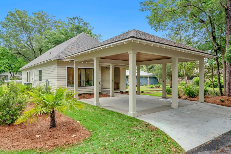Side view of a cottage and covered carport framed by trees
