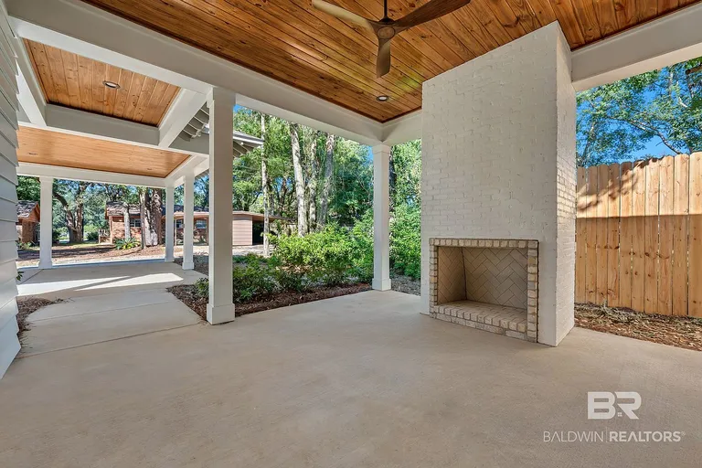 Covered outdoor living area with fireplace and wood ceiling at 410 Azalea St #101