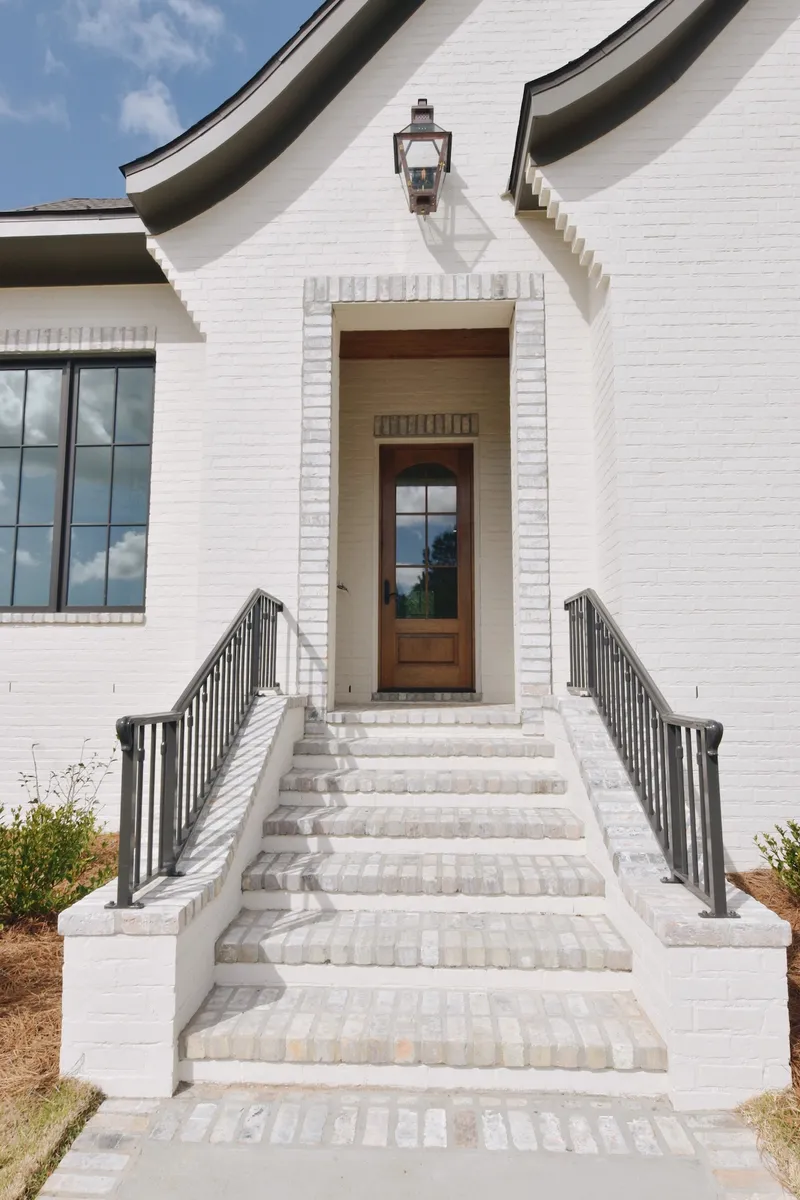 Front steps with black railings leading to a wood entrance door