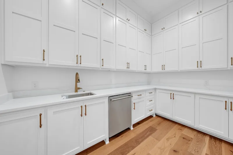 Utility room with white cabinets, a sink and a stainless dishwasher