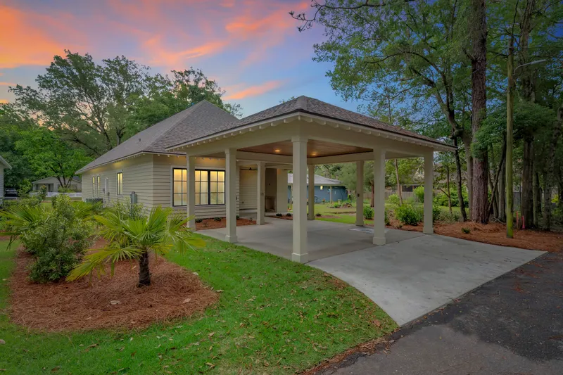Covered carport and cottage exterior with warm lighting at dusk