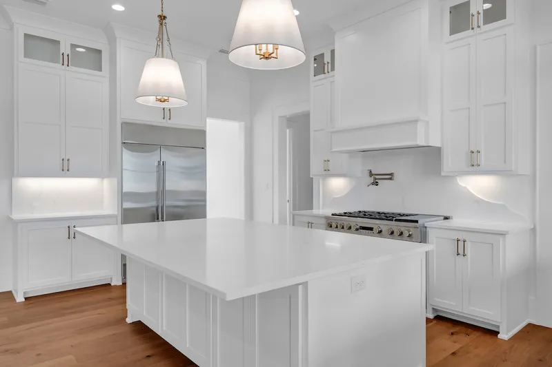 White kitchen cabinetry and a large island beneath pendant lights
