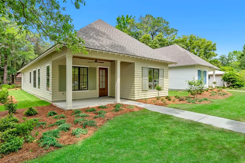 Corner view of a cottage with a covered porch and landscaped lawn
