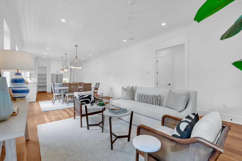 Living area with a sofa and wood-framed chairs beside the dining space