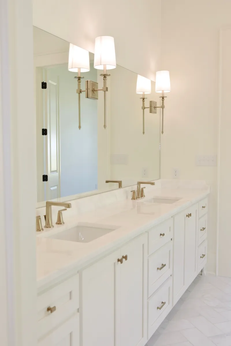 White bathroom vanity with a tall mirror and two wall lights