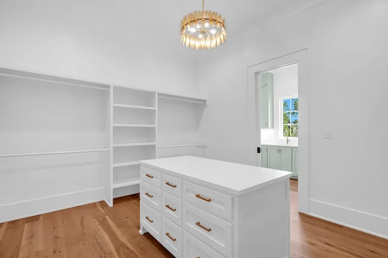 Walk-in closet with open shelving and a central drawer island