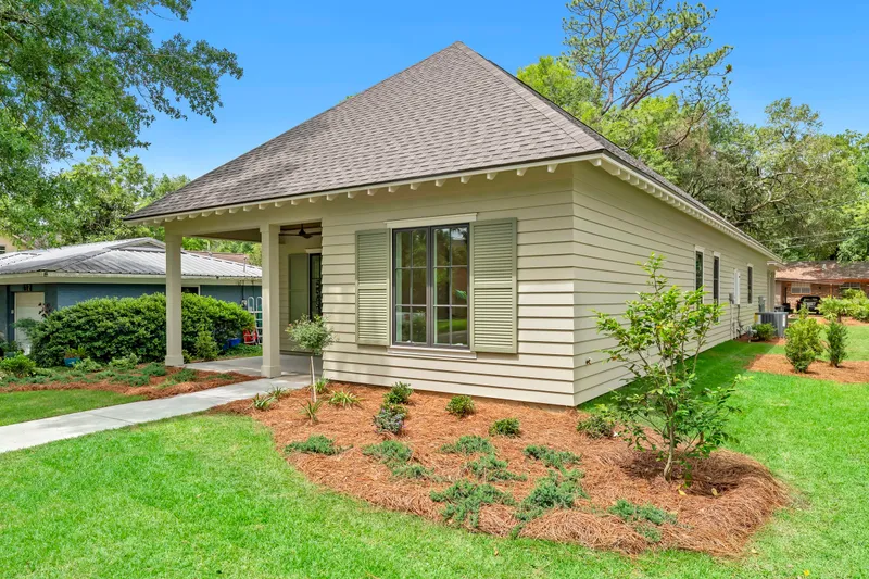 Side view of a cottage porch with flowering plants and mature trees