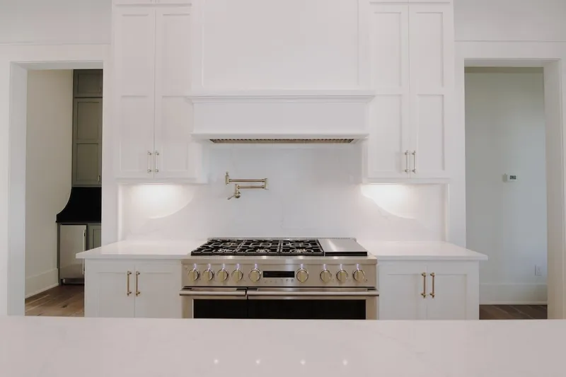 Gas range with a pot filler and white vent hood