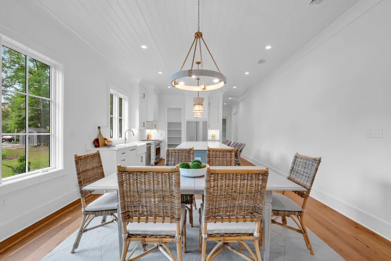 Dining space with woven chairs, a pendant light and views toward the kitchen