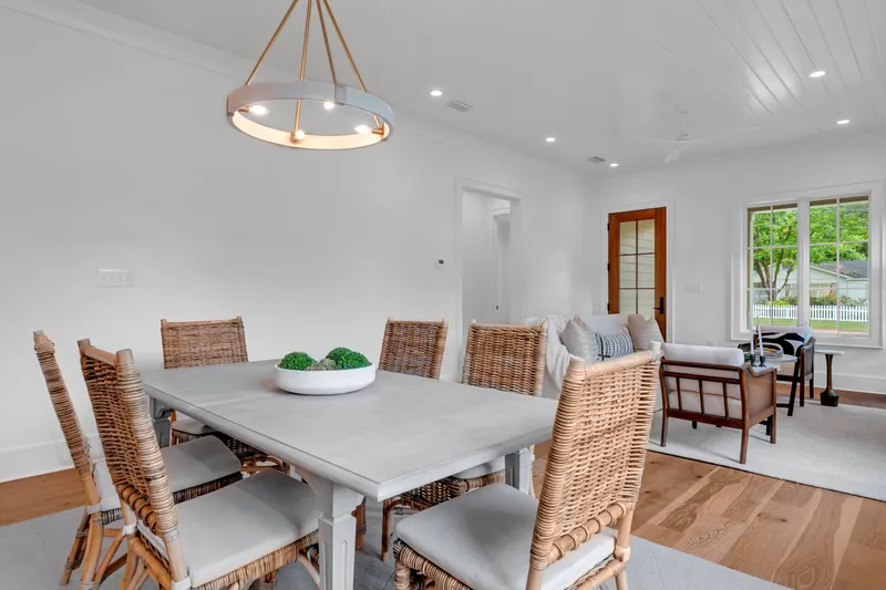 Dining room opening into a furnished living area with tall windows